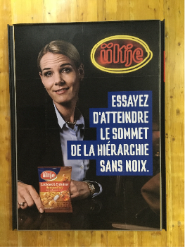 Publicité de ütje montrant une femme tenant un pâque t de noix de la marque accompagnée du slogan " Essayer d'atteindre le sommet de la hiérarchie sans noix.".